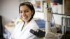 Female scientist smiling next to a microscope, under the programme of the Newton Fund
